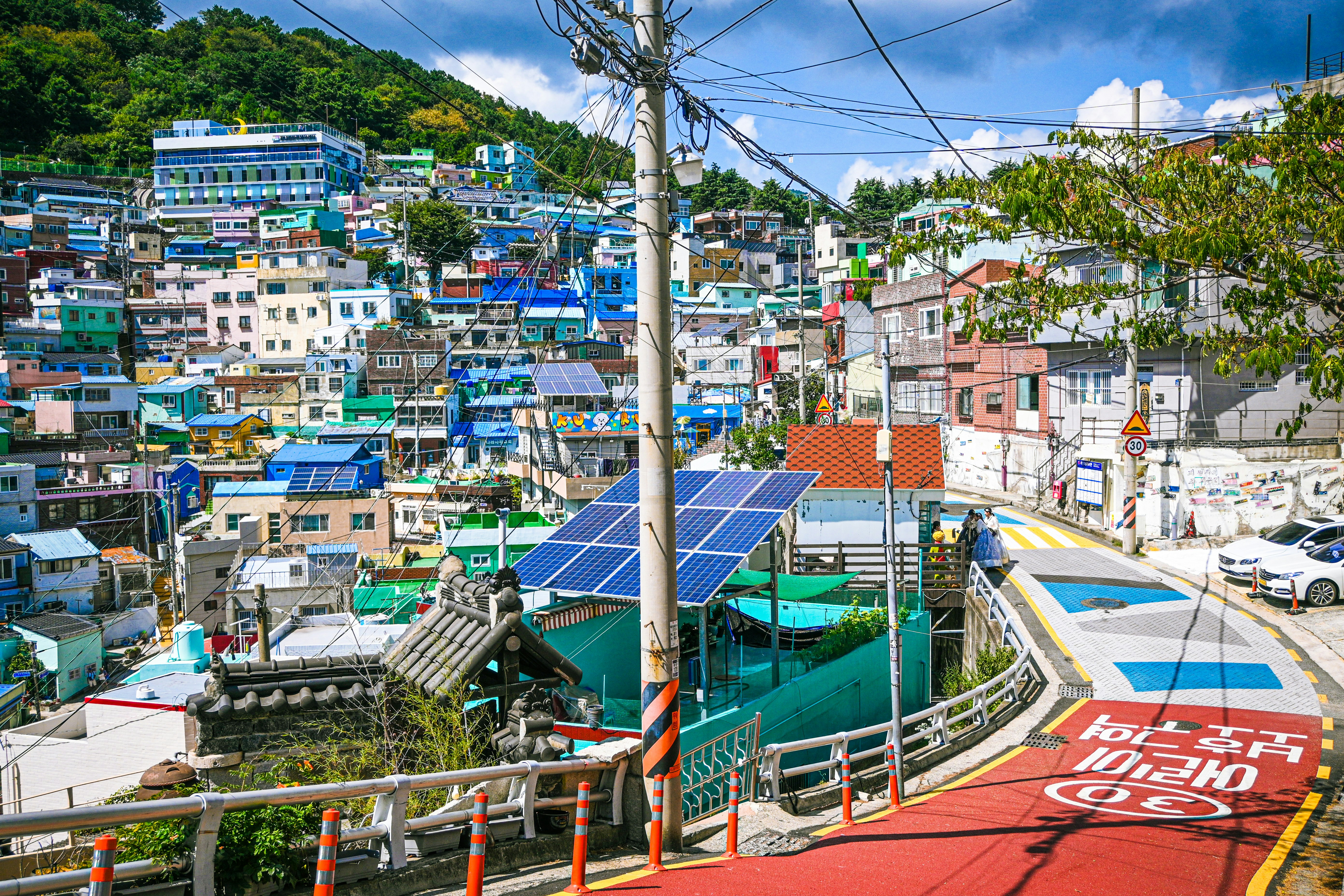 Arrays of solar panels are visible atop buildings in a colorful city on a hill.